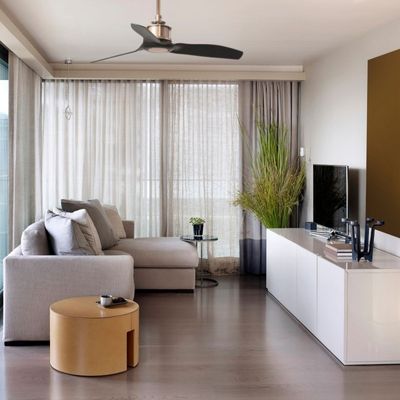 Ventilateur de plafond en rotation dans un salon moderne, carré de canapé gris et table basse, style hiver été pour rafraîchir ou chauffer.
