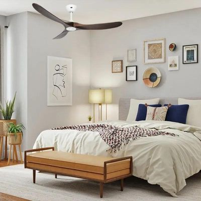 Ventilateur plafond silencieux pour dormir : plafond à trois pales dans une chambre lumineuse et douillette, au-dessus d'un lit.